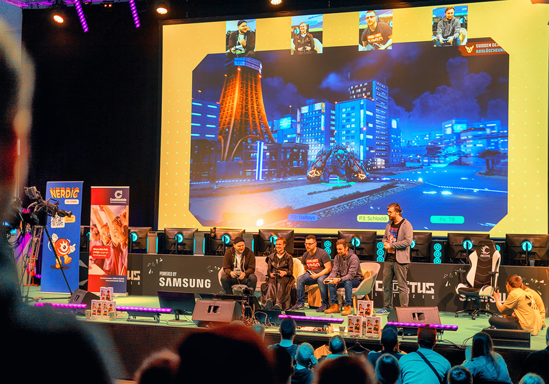 An overview of a stage with people on it playing a game shown on a beamer
